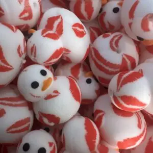 A pile of rubber ducks, white with orange beaks and black eyes, covered in red lip print patterns.