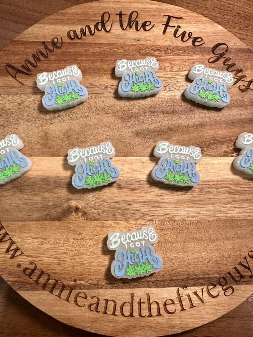 A silicone focal bead displaying several cookies with icing text reading "Because I got high" and decorative grass-like icing. The bead features an inscription saying "Annie and the Five Guys.