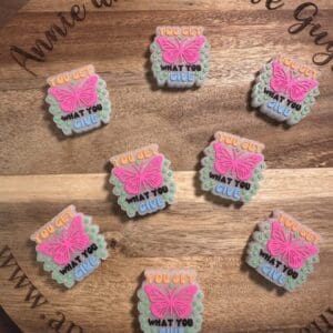 Decorated cookies with pink butterfly designs, featuring the phrase "You get what you give" on a wooden tray, accompanied by a "You get what you give" silicone focal bead.