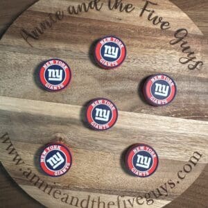 A wooden board featuring "Annie and the Five Guys" around the edge, showcasing six circular New York Football coasters arranged in a pattern.