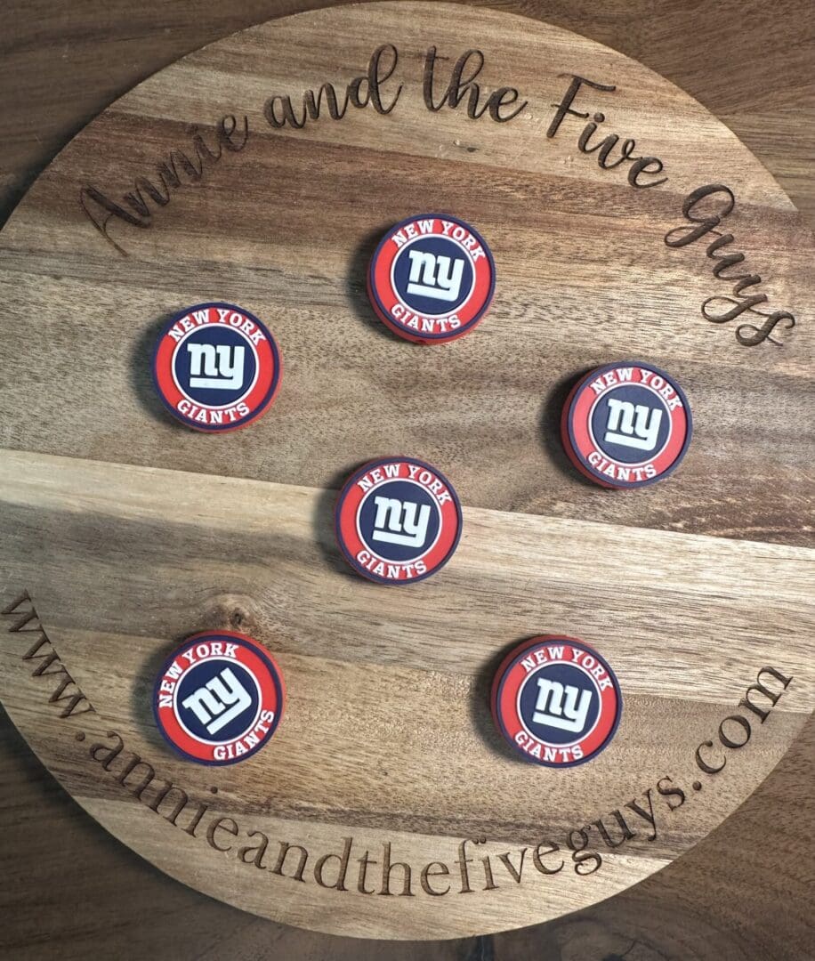 A wooden board featuring "Annie and the Five Guys" around the edge, showcasing six circular New York Football coasters arranged in a pattern.