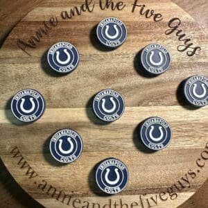 A round wooden board featuring the text "Annie and the Five Guys," adorned with nine circular pins representing the Indianapolis Colts.