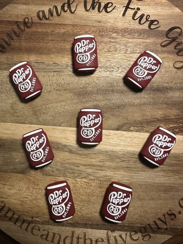 Nine Dr Pepper-themed erasers arranged in a circle on a wooden surface.