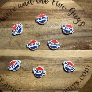 Seven Pepsi bottle cap magnets arranged on a round wooden surface with "Annie and the Five Guys" engraved.