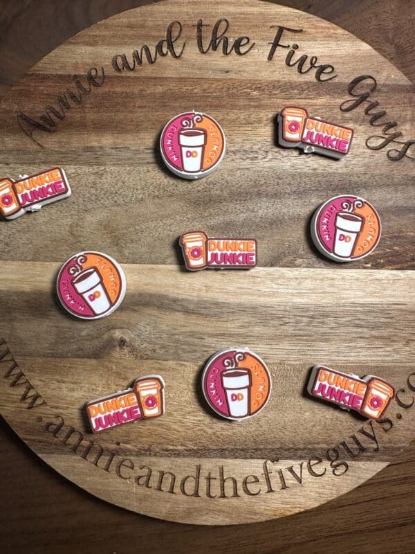 A wooden board displays nine Dunkin' coffee-themed decorative pins arranged in a circle.