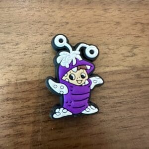 A small cartoon character in a purple bug costume with white wings and antennae on a wooden surface.