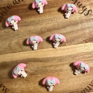 Nine pink and white bunny-shaped pins with blue bows are arranged in rows on a wooden board that is engraved with "annie and the five guys.