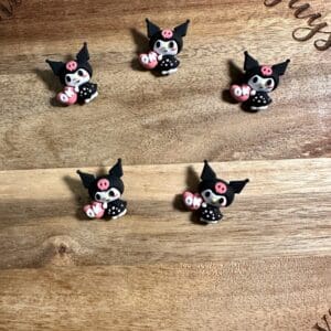 Five small pig-shaped decorations wearing black outfits, arranged on a wooden surface.