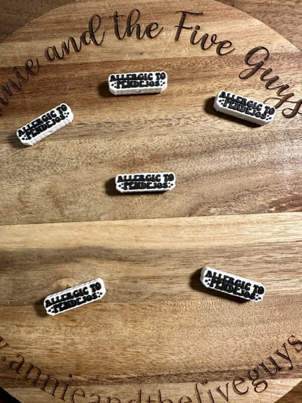 Six small pins on a wooden board, each with the text "ALLERGIC TO FRIDAYS.