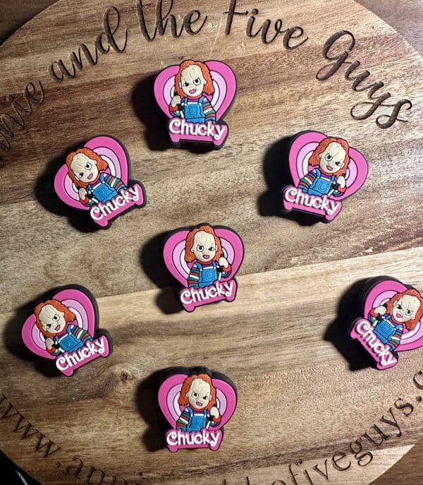 Wooden board with eight Chucky-themed pins arranged in a pattern. Each pin features a cartoon figure with "Chucky" written below.