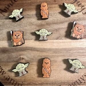 Wooden board displaying various wooden pins shaped like sci-fi characters with an engraved website link.