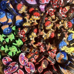 A variety of colorful, cartoon character keychains are scattered on a wooden surface.