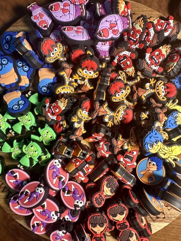 A variety of colorful, cartoon character keychains are scattered on a wooden surface.