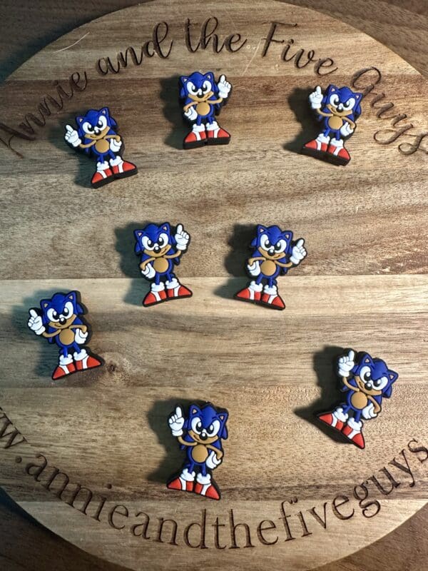 Pins featuring a cartoon hedgehog in red shoes are arranged on a round wooden board.