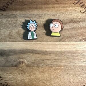 Two cartoon character pins are placed on a wooden circular board with carved text.