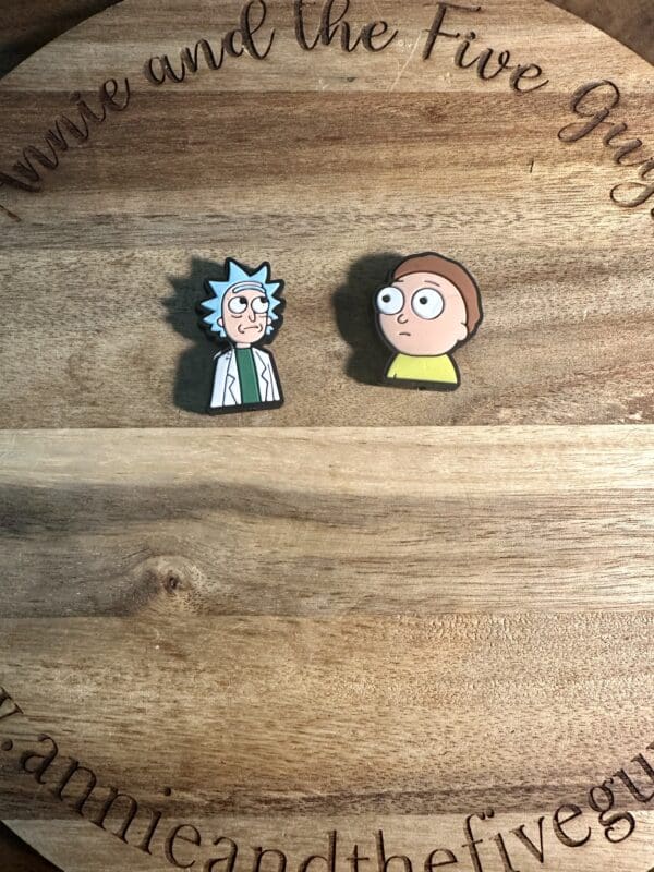 Two cartoon character pins are placed on a wooden circular board with carved text.