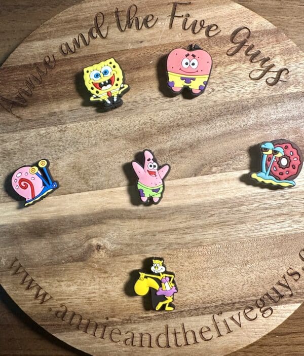 Round wooden board with six cartoon character pins from a popular animated series.