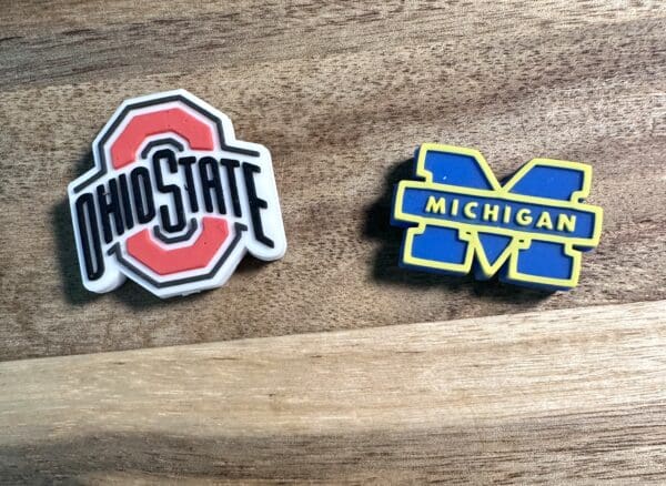 Ohio State logo and Michigan logo on a wooden surface.