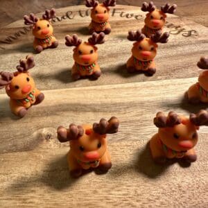 Clay reindeer figurines with scarves are arranged on a wooden surface.