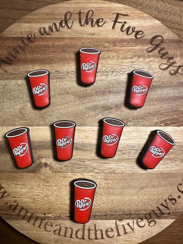 Seven Dr Pepper magnets arranged on a wooden surface with text "Annie and the Five Guys" visible.