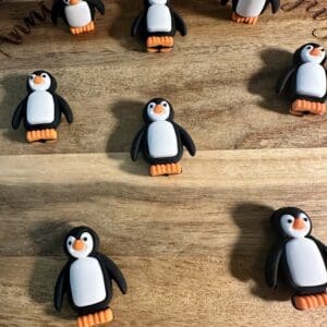 Seven penguin-shaped cookies are arranged on a wooden board.