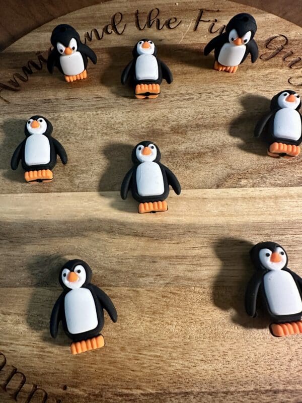 Seven penguin-shaped cookies are arranged on a wooden board.