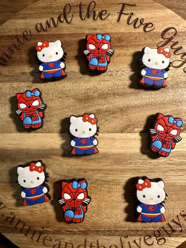 Nine custom cookies on a wooden board, featuring Hello Kitty and Spider-Man designs.