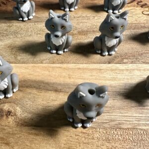 Several small, gray wolf figurines with white accents and yellow eyes are arranged on a wooden surface.