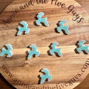 Wooden round tray with the text "Annie and the Five Guys" holds ten decorated blue reindeer-shaped cookies.