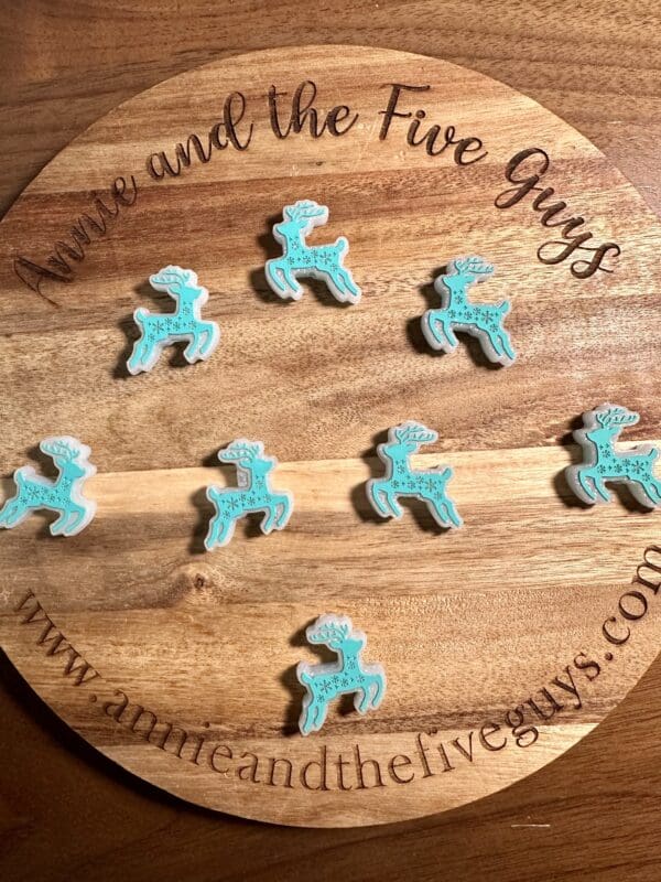 Wooden round tray with the text "Annie and the Five Guys" holds ten decorated blue reindeer-shaped cookies.