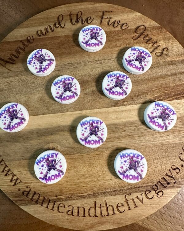 Wooden platter with ten round "Hockey Mom" decorated cookies, featuring a purple hockey player silhouette.