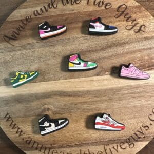 Wooden board with text, displaying seven small, colorful sneaker-shaped pins.