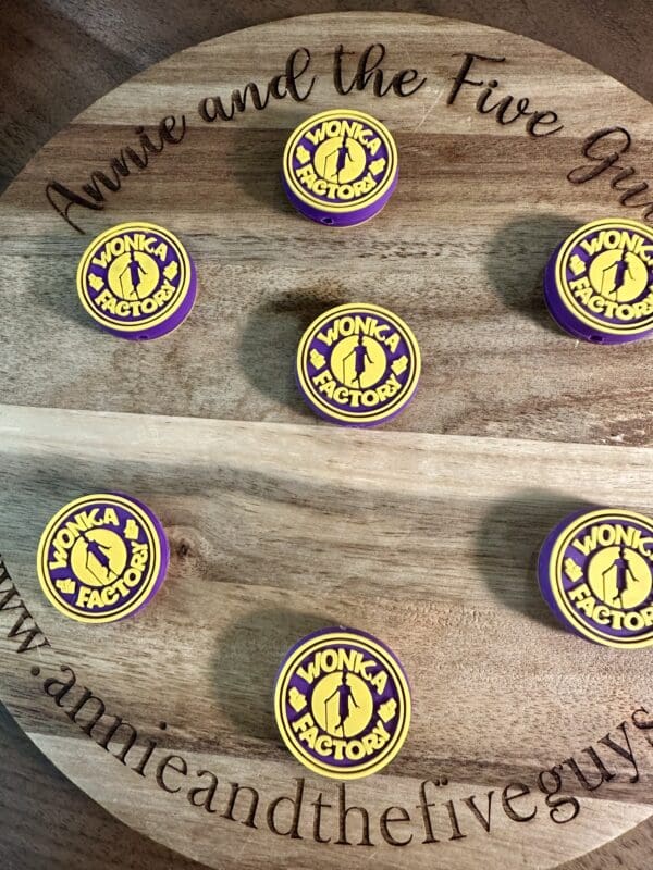 Round wooden board with six purple and yellow Wonka Factory logo cookies. Engraved text reads "Annie and the Five Guys.