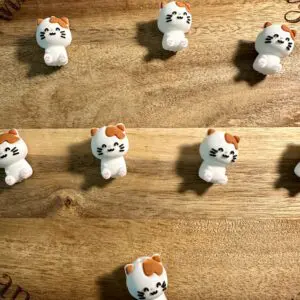 Small cat figurines with various expressions are arranged on a wooden surface.