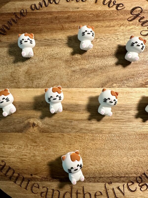 Small cat figurines with various expressions are arranged on a wooden surface.